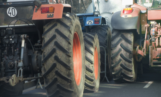 Trekkers – Rear view of multicolored tractors, wheels and engines.