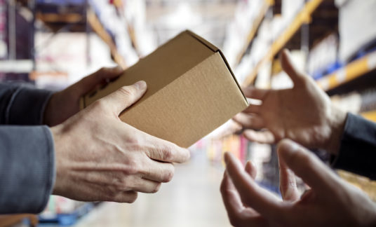 Worker with package in a distribution warehouse