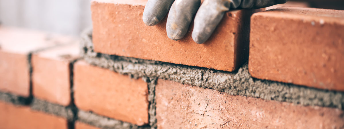 Close up of industrial bricklayer installing bricks on construction site