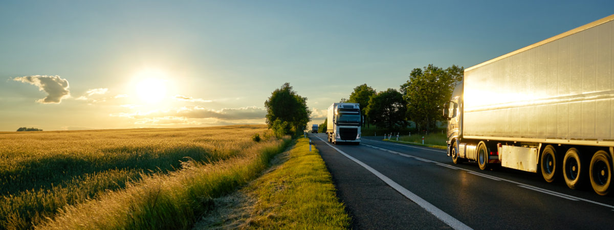 Trucks moving against each other on the road at sunset.