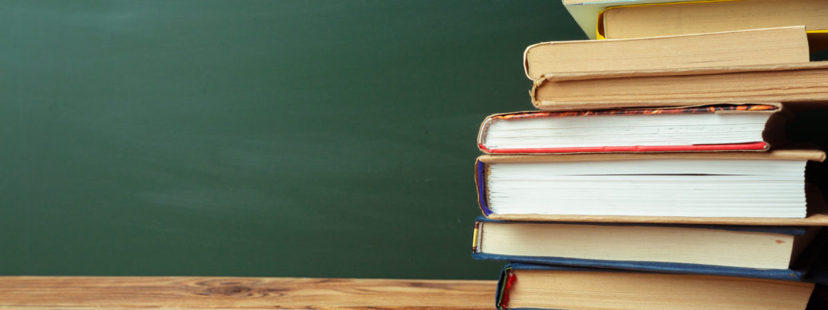 Classroom with blackboard, wooden table and books