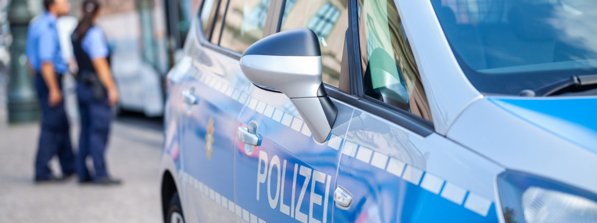 German police car stands on street. Two police officers controls traffic. Polizei is the german word for police