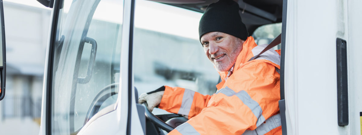 Hispanic truck driver sitting in vehicle, at warehouse